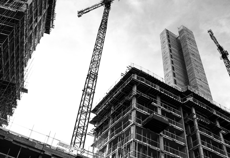 Grayscale photo of crane in front of building