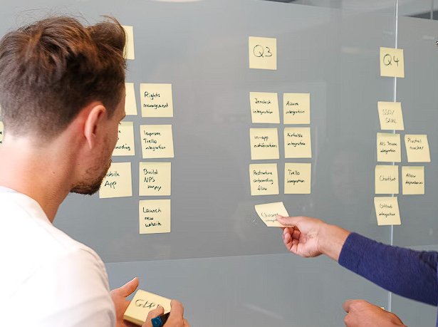 Two men putting sticky papers on wall