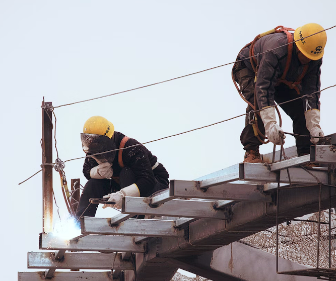 Workers in black jacket and yellow helmets standing on top of the building